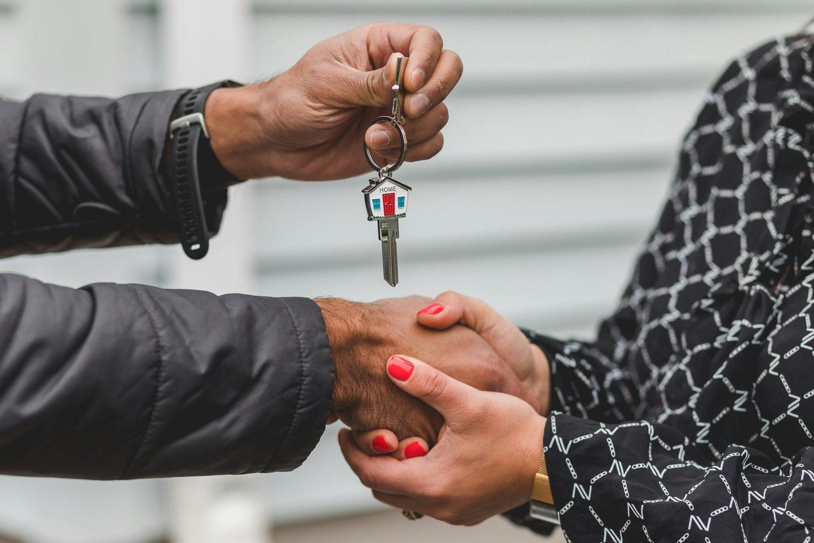 A Mortgage Broker and a client shaking hands while handing over new house keys